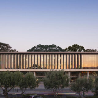 Long building clad in glass, raised among the trees